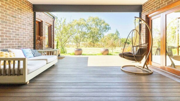 A spacious patio with a wooden deck, a hanging chair, and a sofa with cushions. - Cascade Cottage: Spacious Family Retreat in Keysborough Garden Parking Sleeps 8 (Keysborough)