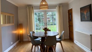 A dining area with a round table, four chairs, a hanging light fixture, a window with curtains, and a radiator. - Uphill Lincoln Home, Near Cathedral and Castle (Lincoln)