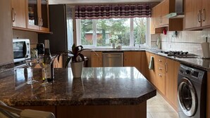 A kitchen with wooden cabinets, a granite countertop, a built-in microwave, a dishwasher, and a washing machine. - Uphill Lincoln Home, Near Cathedral and Castle (Lincoln)