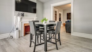 A dining area with a modern table and chairs, a flat-screen TV mounted above, and a fireplace with a brick surround. - Walk to Trolley District: Olde Towne East Retreat (Columbus)