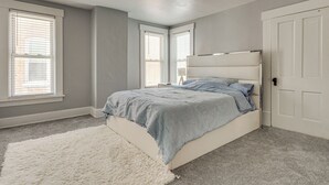 A bedroom with a bed, a white rug, and two windows with blinds. - Walk to Trolley District: Olde Towne East Retreat (Columbus)