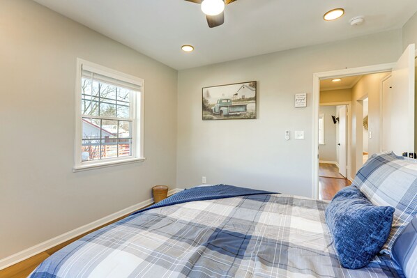 A bedroom with a bed, a window, a painting, and a door leading to another room. - Stay in the Heart of London! Walkable, Modern Home (London)