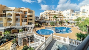 Um resort com várias piscinas, um pátio central e uma variedade de varandas.