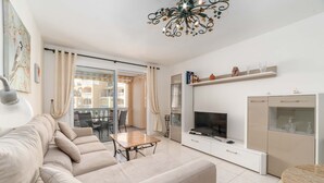 Uma sala de estar moderna com sofá, TV e área de refeições.