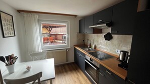 Eine kleine Küche mit Fenster, Holztisch und modernen Geräten.