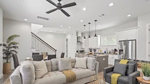A modern kitchen with white cabinets, a stainless steel refrigerator, and pendant lighting.
