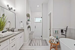 Ein modernes Badezimmer mit großem Spiegel, weißen Schränken, einer Badewanne und einer Duschkabine.