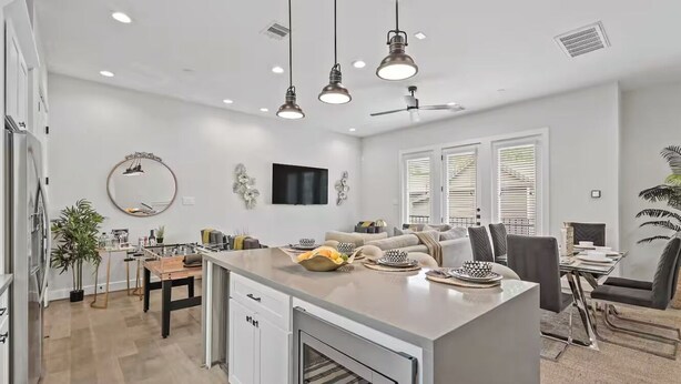 A modern kitchen with a central island, built-in oven, and pendant lighting.