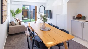 Una cocina moderna con una mesa de comedor de madera, sillas negras y un armario blanco.