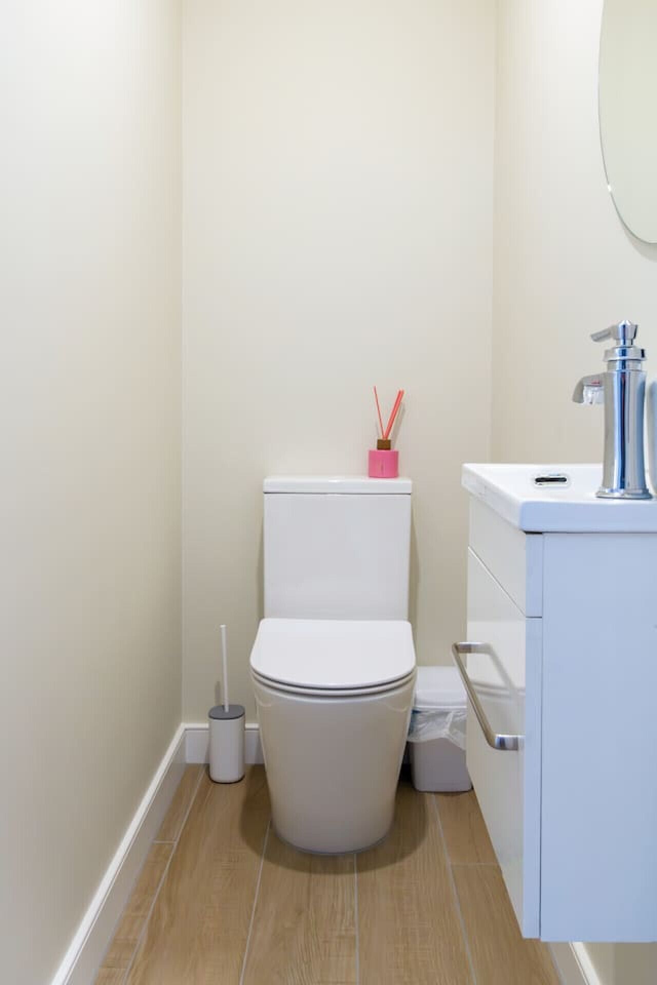 A small, modern bathroom with a white toilet, a sink, and a mirror.