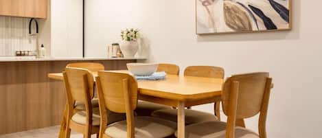 Un coin repas avec une table et des chaises en bois, un vase rempli de fleurs et un tableau accroché au mur.