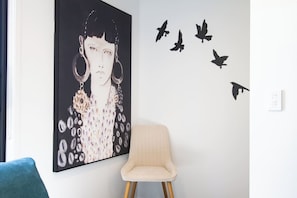 A room with a large abstract painting, a chair, and bird silhouettes on the wall.