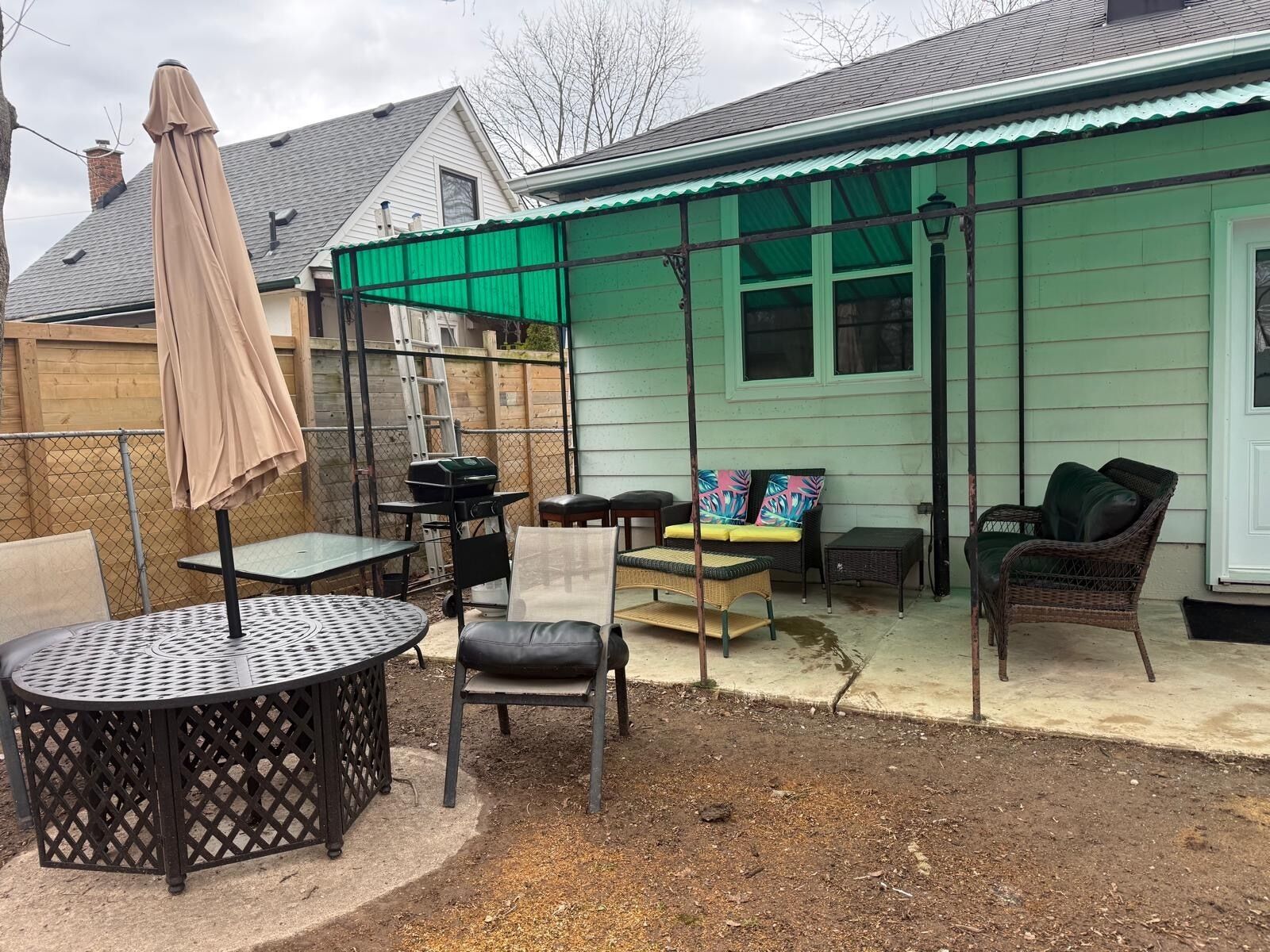 A patio with outdoor furniture, a grill, and a covered area with a green roof.