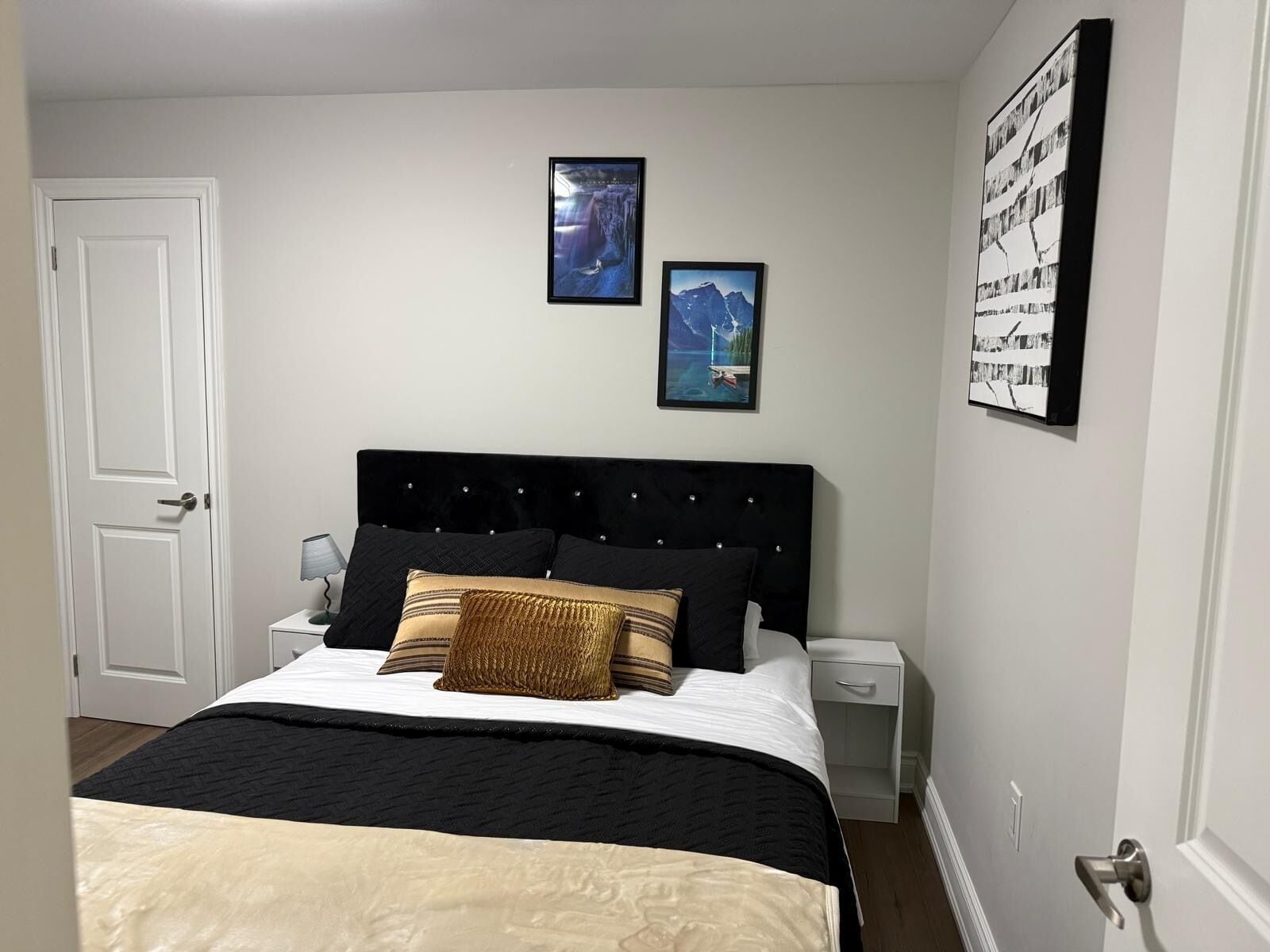 A bedroom with a bed, two bedside tables, and two framed pictures on the wall.