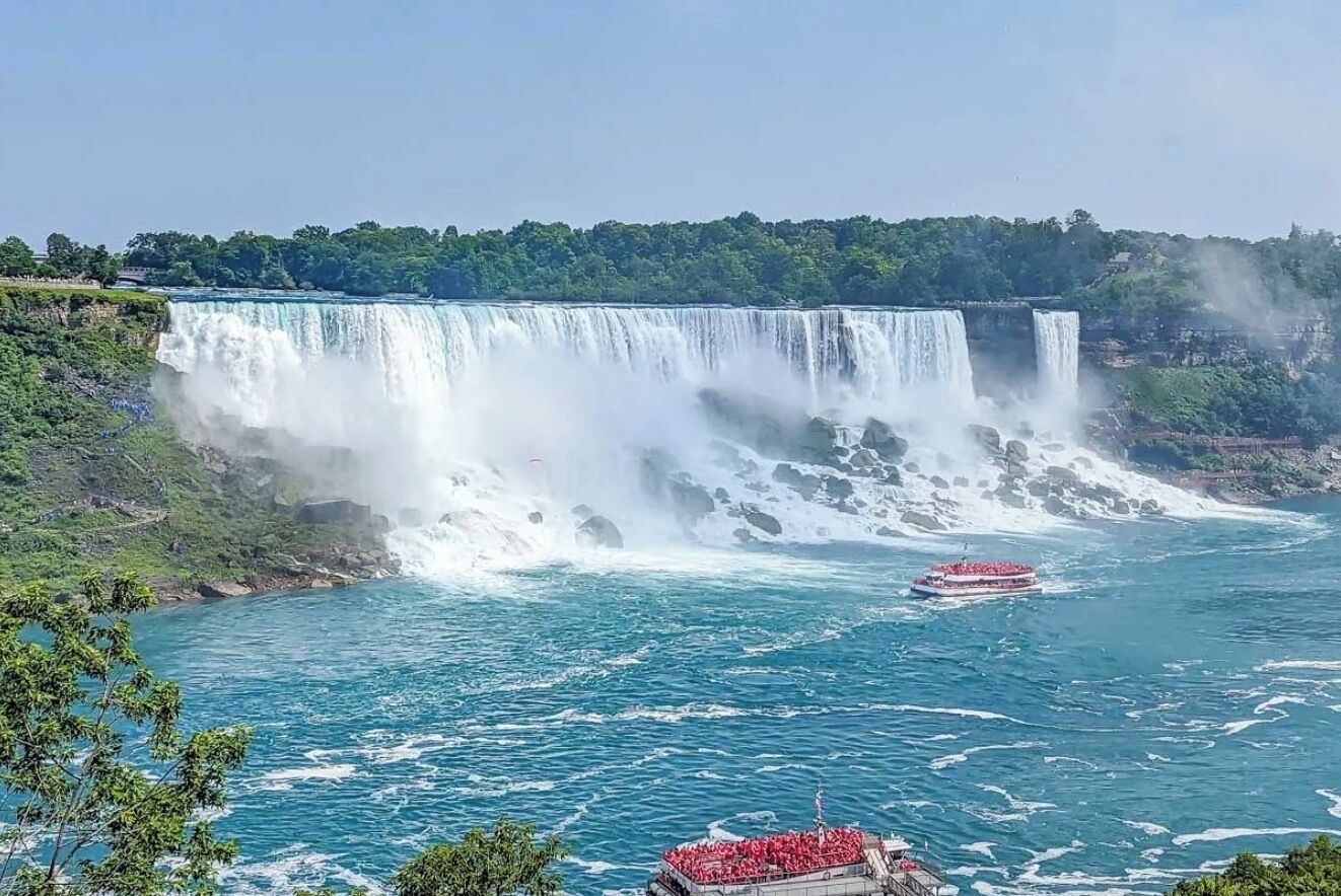 Een grote waterval met bootjes op het water.