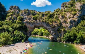A natural rock arch over a beach with kayaks and people. - Maison proche rivière (Mejannes le clap)
