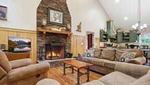 A living room with a stone fireplace, a television, and a sofa.