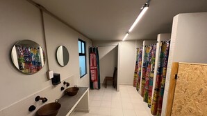 A modern bathroom with a long vanity, two sinks, a mirror, and a shower area with colorful shower curtains. - Nomadik - COMMUNITY - C1 (Heroica Puebla de Zaragoza)