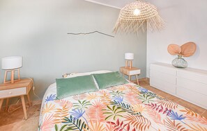 A bedroom with a bed, a bedside table, a lamp, a wall-mounted light fixture, and a dresser. - Maison avec piscine privée (Mazan)