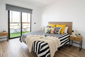 Ein Schlafzimmer mit einem großen Bett, einem Nachttisch, einer Lampe und Blick auf eine Terrass.