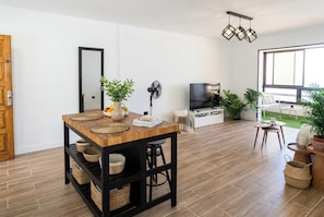 Ein modernes Wohnzimmer mit einem Holzesstisch, einem Fernseher und einem großen Fenster.
