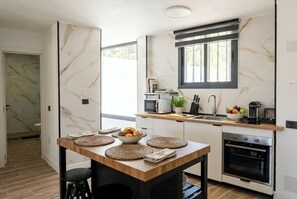 Eine moderne Küche mit Marmor-Spritzschutz, einem Holzespeisetisch und einem eingebauten Backofen.