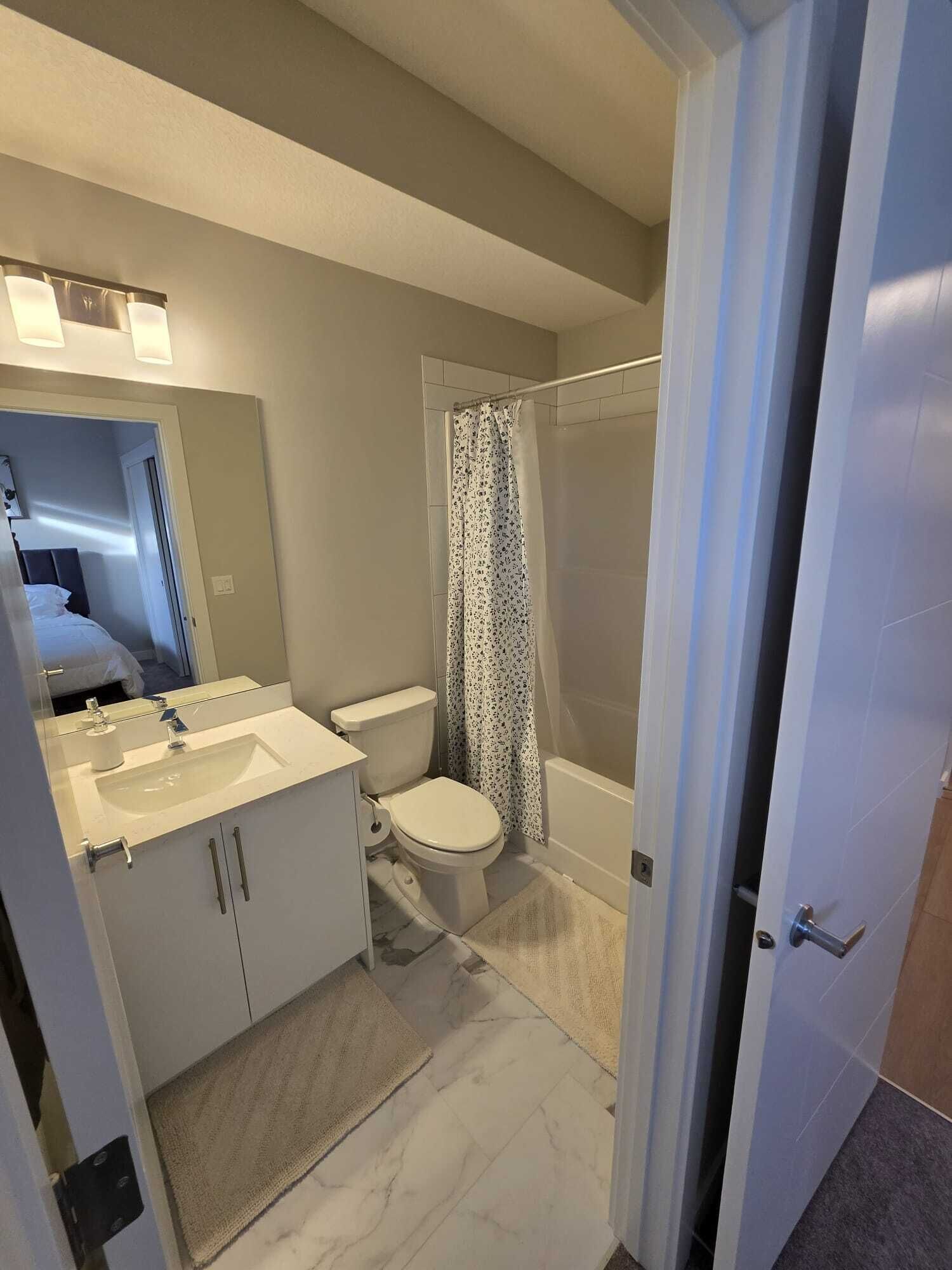 Ein modernes Badezimmer mit Waschbecken, Toilette und Duschbereich in Weiß.