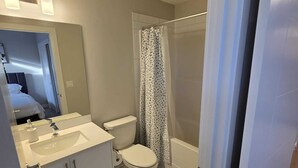Un bagno moderno con lavandino, WC e zona doccia, tutti in bianco.