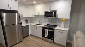 Una cucina moderna con mobili bianchi, elettrodomestici in acciaio inossidabile e pavimento in legno.
