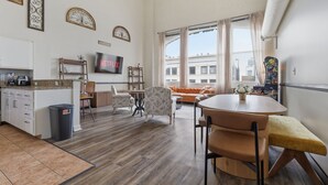 A modern living room with a kitchen area, a dining table, and a sofa.