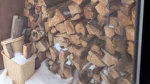 Ein hölzernes Gartenhaus mit einem Holzstapel darin.