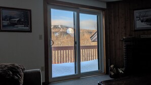 Ein Zimmer mit einer Schiebetür zu einem Deck mit Blick auf eine verschneite Landschaft und einem Holzzaun.