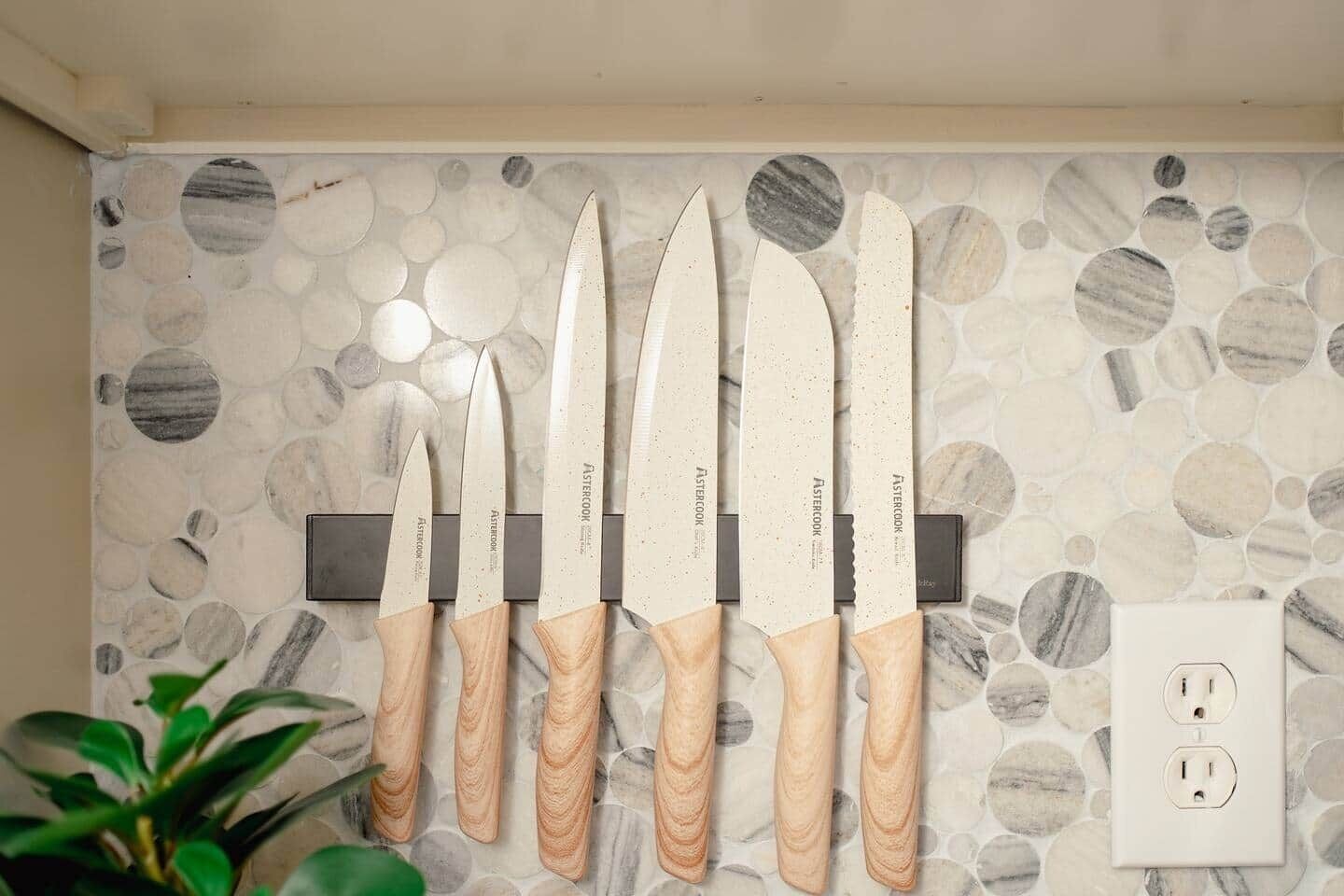 A wall-mounted knife set with wooden handles and a stone-patterned backsplash.