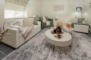 Ein Wohnzimmer mit einem weißen Sofa, einem grünen Sofa, einem runden Couchtisch und einer Lampe.