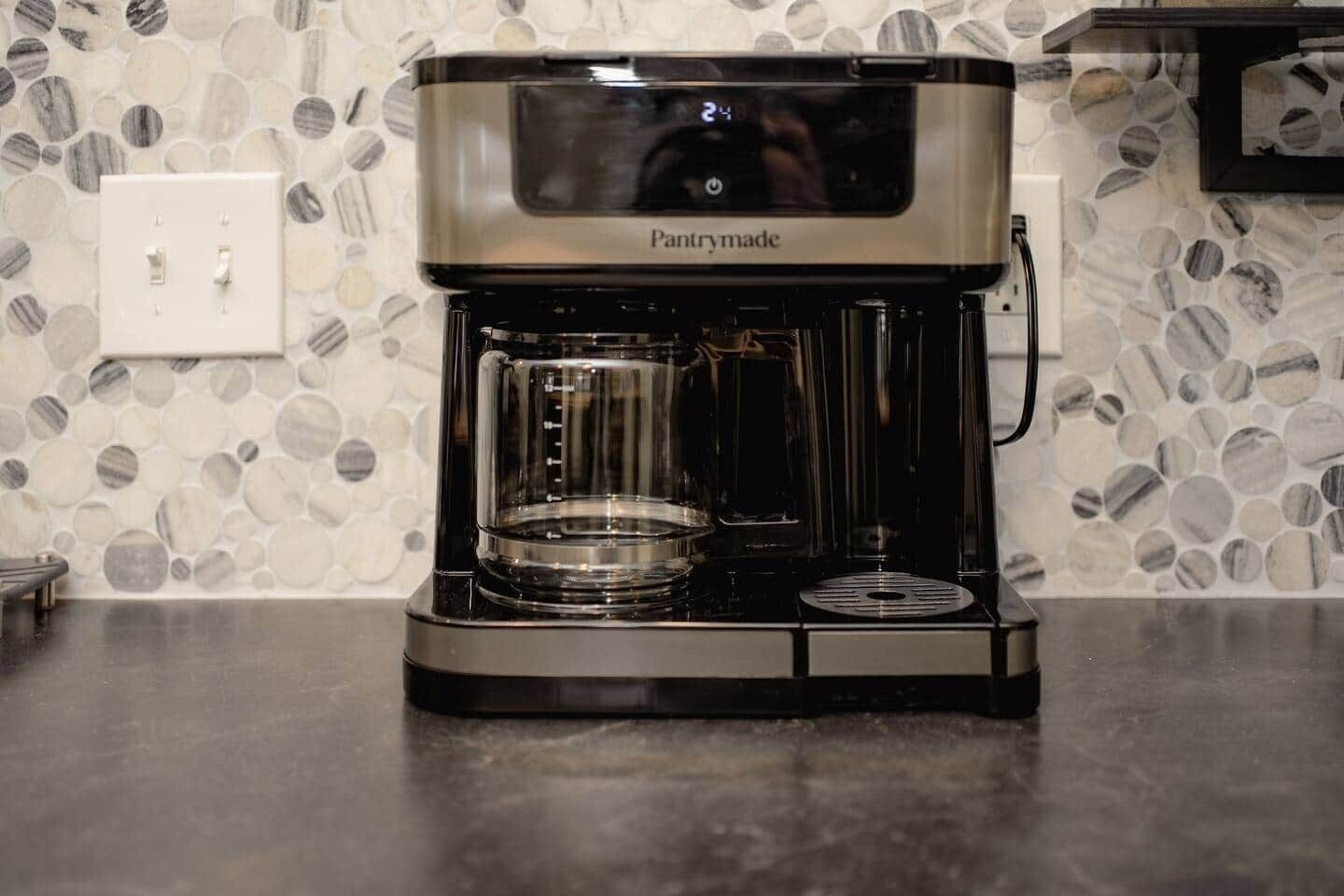 A Pantrymade coffee maker on a countertop with a mosaic tile backsplash.