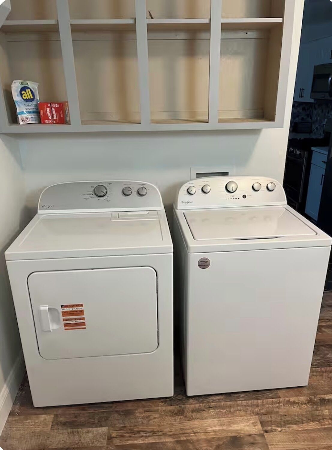 Two white front-loading washing machines in a laundry room with wooden flooring.