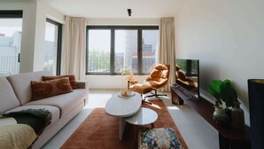 Un salon moderne avec un canapé, un fauteuil, une table basse et un téléviseur.