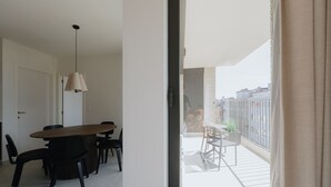 Un appartement moderne doté d’un coin repas, d’un balcon et offrant une vue sur la ville.