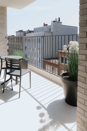 Un balcone con tavolo e sedie, una pianta in vaso e vista sugli edifici.