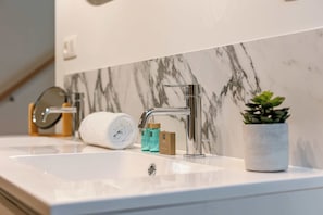 A modern bathroom with a white marble sink, a chrome faucet, and a small potted plant. - Modern Suite in the Heart of the City (Antwerpen)