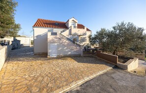 A two-story building with a tiled roof, a stone-paved courtyard, and a small outdoor seating area. - Amazing home in Kastel Sucurac (Kastel Sucurac)