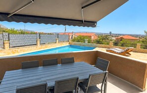 A rooftop pool with a table and chairs, surrounded by a stone wall and a view of the city. - Amazing home in Kastel Sucurac (Kastel Sucurac)
