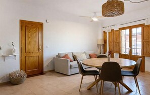 A dining area with a round table and chairs, a sofa, a wooden door, and a window with a view. - 1 bedroom awesome apartment in Denia (Denia)