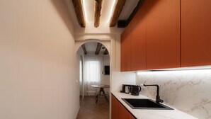 A modern kitchen with a marble countertop, a black sink, and orange cabinetry. - Cà del Bacino, San Marco (Venice)