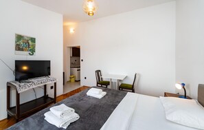 Ein Hotelzimmer mit Bett, Schreibtisch mit Fernseher, Stuhl und kleinem Tisch.