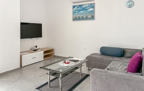 A modern living room with a flat-screen TV, a glass-top coffee table, a grey sofa, and a small side table with a bowl and remote control. - 2 bedroom beautiful apartment in Cizici (Cizici)
