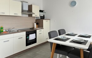 A modern kitchen with a built-in oven, a microwave, and a dining area with a table set for four. - 2 bedroom beautiful apartment in Cizici (Cizici)