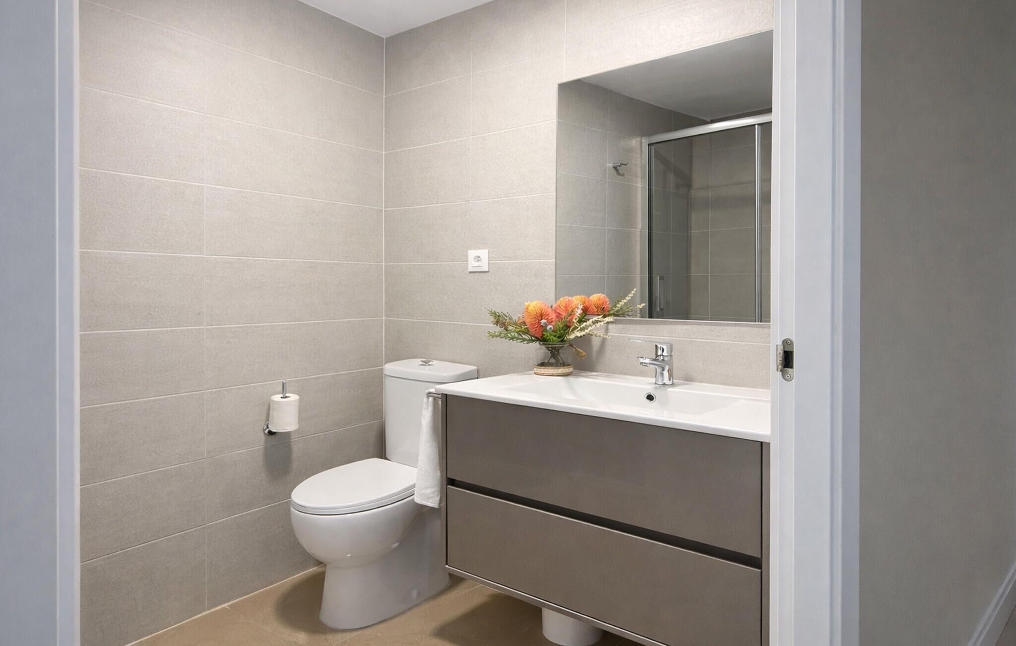 A modern bathroom with a toilet, sink, and mirror.