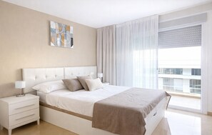 A modern bedroom with a large bed, a bedside table, a nightstand, and a window with curtains. - Beautiful apartment in Cabanes with house sea view (Cabanes)