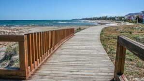 A wooden boardwalk leading to a beach with a clear view of the ocean and distant buildings. - 3 bedroom gorgeous apartment in Cabanes (Cabanes)